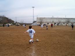 superficie de tierra campo de fútbol, niños jugando en cancha grande